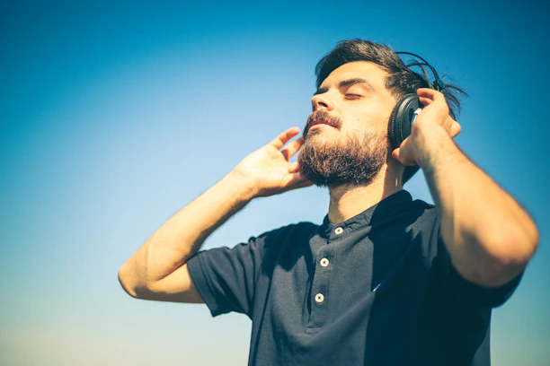 man in black polo shirt holding his head