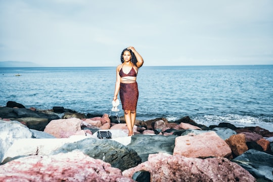 woman in black bikini standing on rocky shore during daytime in Puerto Vallarta Mexico