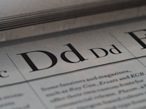 Close-up of a printed page featuring the letter 'Dd' in various fonts. The text is lined and the background has a slight texture making it appear like a page from a typography book or manual.