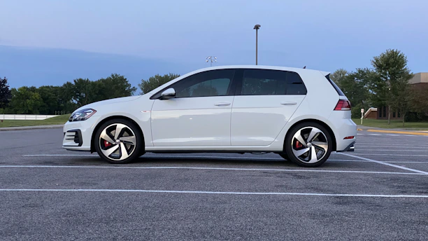 A single clean, drivable used car parked in an open lot under clear skies.