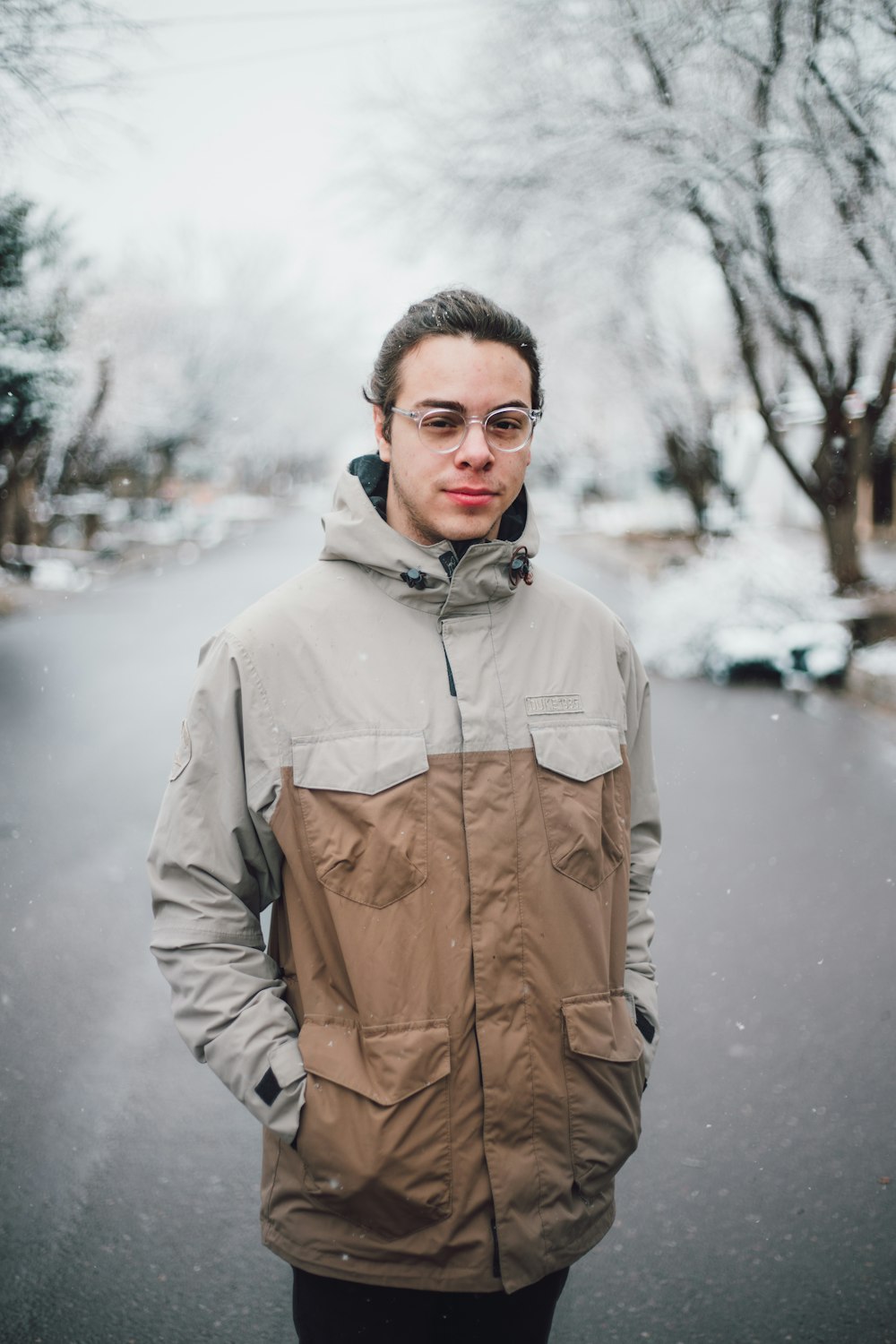 man in brown jacket standing on snow covered ground during daytime