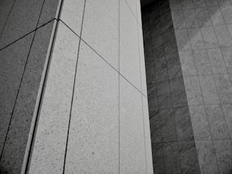 Geometric patterns formed by concrete or stone tiles arranged in a grid-like pattern. The surface features clean lines and large rectangular panels with a mix of textures.