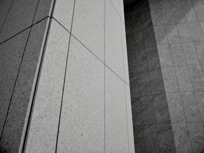 Geometric patterns formed by concrete or stone tiles arranged in a grid-like pattern. The surface features clean lines and large rectangular panels with a mix of textures.