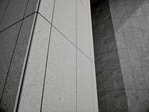 Geometric patterns formed by concrete or stone tiles arranged in a grid-like pattern. The surface features clean lines and large rectangular panels with a mix of textures.