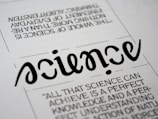 A close-up view of a typography artwork featuring the word 'science' in a stylized, script-like black font against a white background. Below it, there is a quote about science written in a smaller, sans-serif font. Above the main word, there is another sentence printed upside-down.