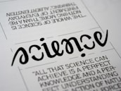 A close-up view of a typography artwork featuring the word 'science' in a stylized, script-like black font against a white background. Below it, there is a quote about science written in a smaller, sans-serif font. Above the main word, there is another sentence printed upside-down.