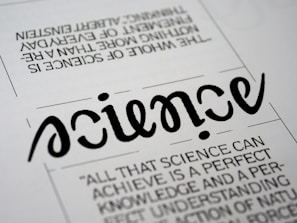 A close-up view of a typography artwork featuring the word 'science' in a stylized, script-like black font against a white background. Below it, there is a quote about science written in a smaller, sans-serif font. Above the main word, there is another sentence printed upside-down.