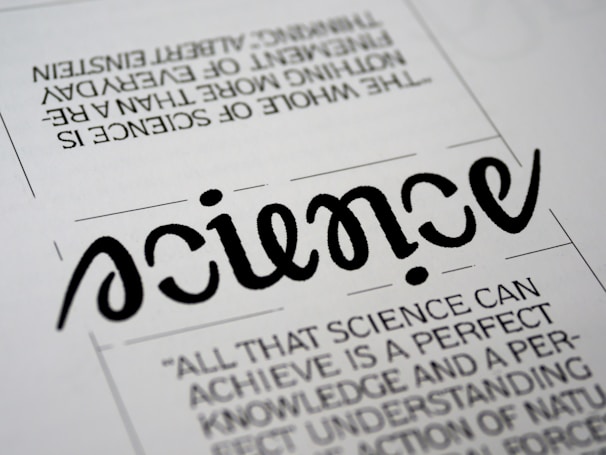 A close-up view of a typography artwork featuring the word 'science' in a stylized, script-like black font against a white background. Below it, there is a quote about science written in a smaller, sans-serif font. Above the main word, there is another sentence printed upside-down.