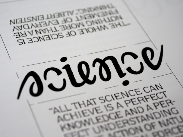A close-up view of a typography artwork featuring the word 'science' in a stylized, script-like black font against a white background. Below it, there is a quote about science written in a smaller, sans-serif font. Above the main word, there is another sentence printed upside-down.