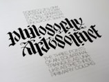 A piece of calligraphy art displaying stylized, elaborately designed text. The primary focus is the words 'Philosophy' and 'Art & Science' written in a bold, gothic font. Beneath, there is smaller printed text describing concepts related to equilateral triangles and primary colors, adding a philosophical dimension.