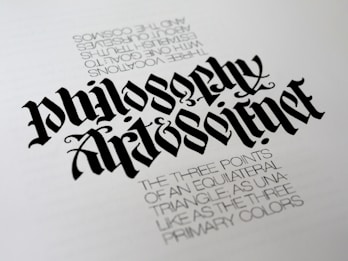 A piece of calligraphy art displaying stylized, elaborately designed text. The primary focus is the words 'Philosophy' and 'Art & Science' written in a bold, gothic font. Beneath, there is smaller printed text describing concepts related to equilateral triangles and primary colors, adding a philosophical dimension.