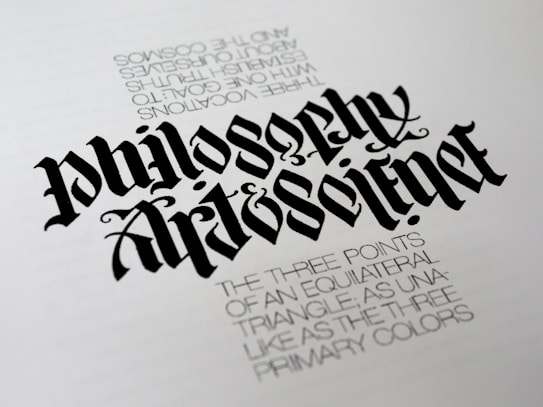 A piece of calligraphy art displaying stylized, elaborately designed text. The primary focus is the words 'Philosophy' and 'Art & Science' written in a bold, gothic font. Beneath, there is smaller printed text describing concepts related to equilateral triangles and primary colors, adding a philosophical dimension.