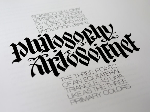 A piece of calligraphy art displaying stylized, elaborately designed text. The primary focus is the words 'Philosophy' and 'Art & Science' written in a bold, gothic font. Beneath, there is smaller printed text describing concepts related to equilateral triangles and primary colors, adding a philosophical dimension.