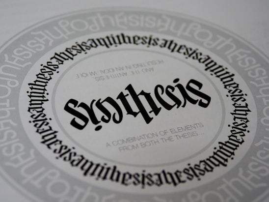 A detailed and symmetrical text design with the word 'synthesis' prominently displayed in the center in a gothic-style font. The word is surrounded by circular text patterns repeating the word 'synthesis' in a smaller font size, creating a visually hypnotic effect. Smaller text underneath the central word reads 'A combination of elements from both the thesis...'