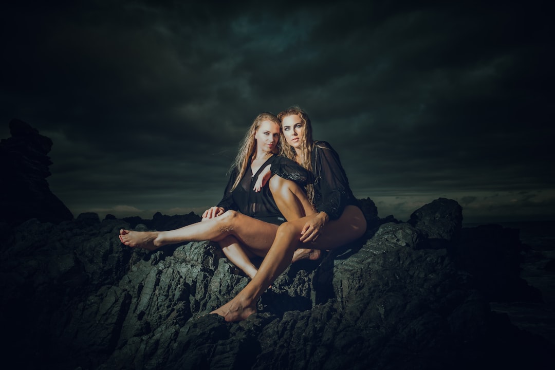 woman in black dress sitting on rock formation during night time