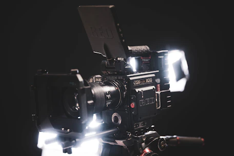 A sleek modern camera setup capturing a cinematic scene with red and black lighting accents.