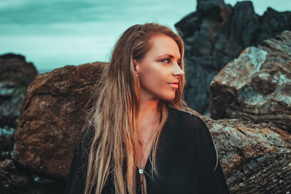 woman in black long sleeve shirt standing on rocky hill during daytime