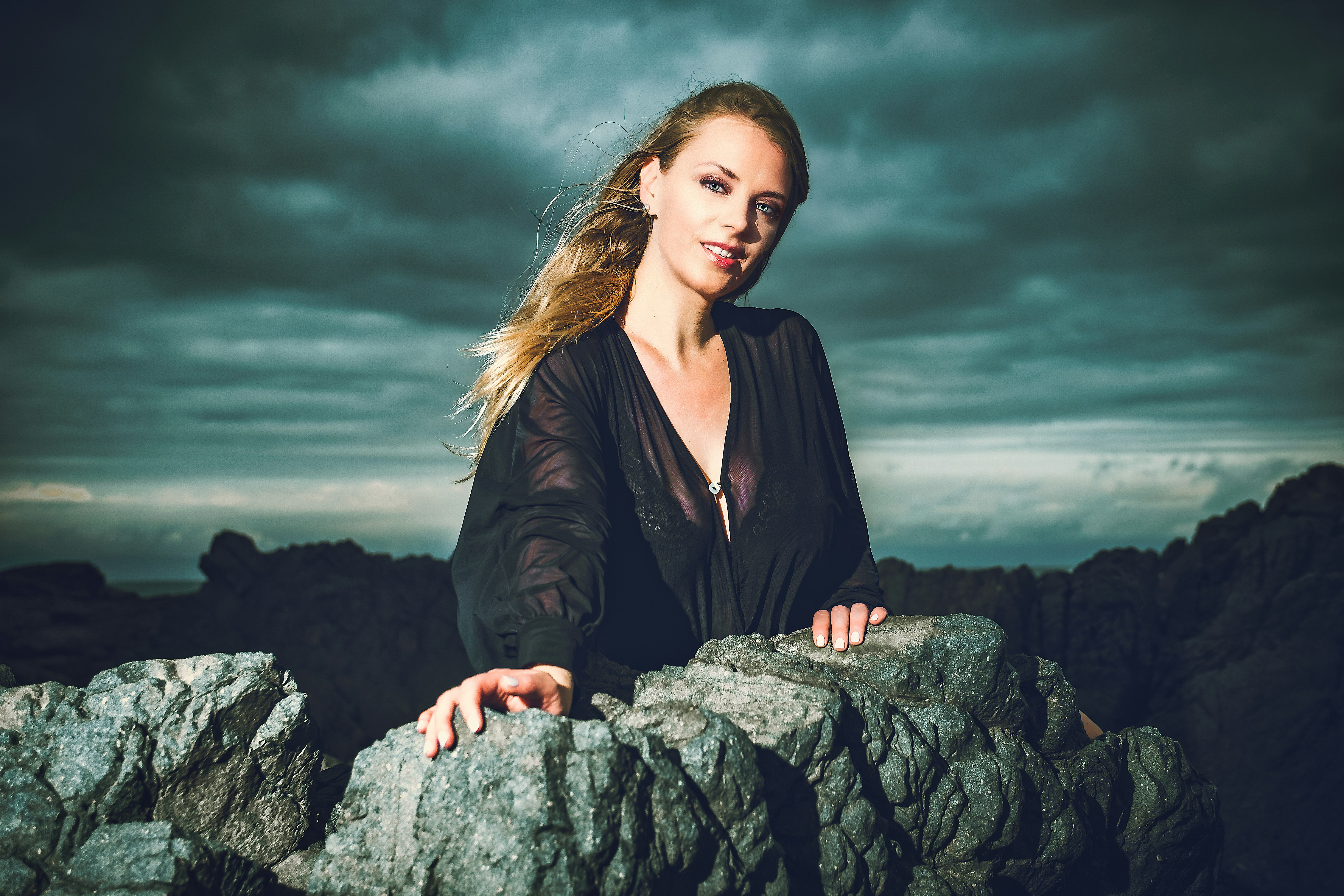 Beautiful model wearing black with huge rocks as background