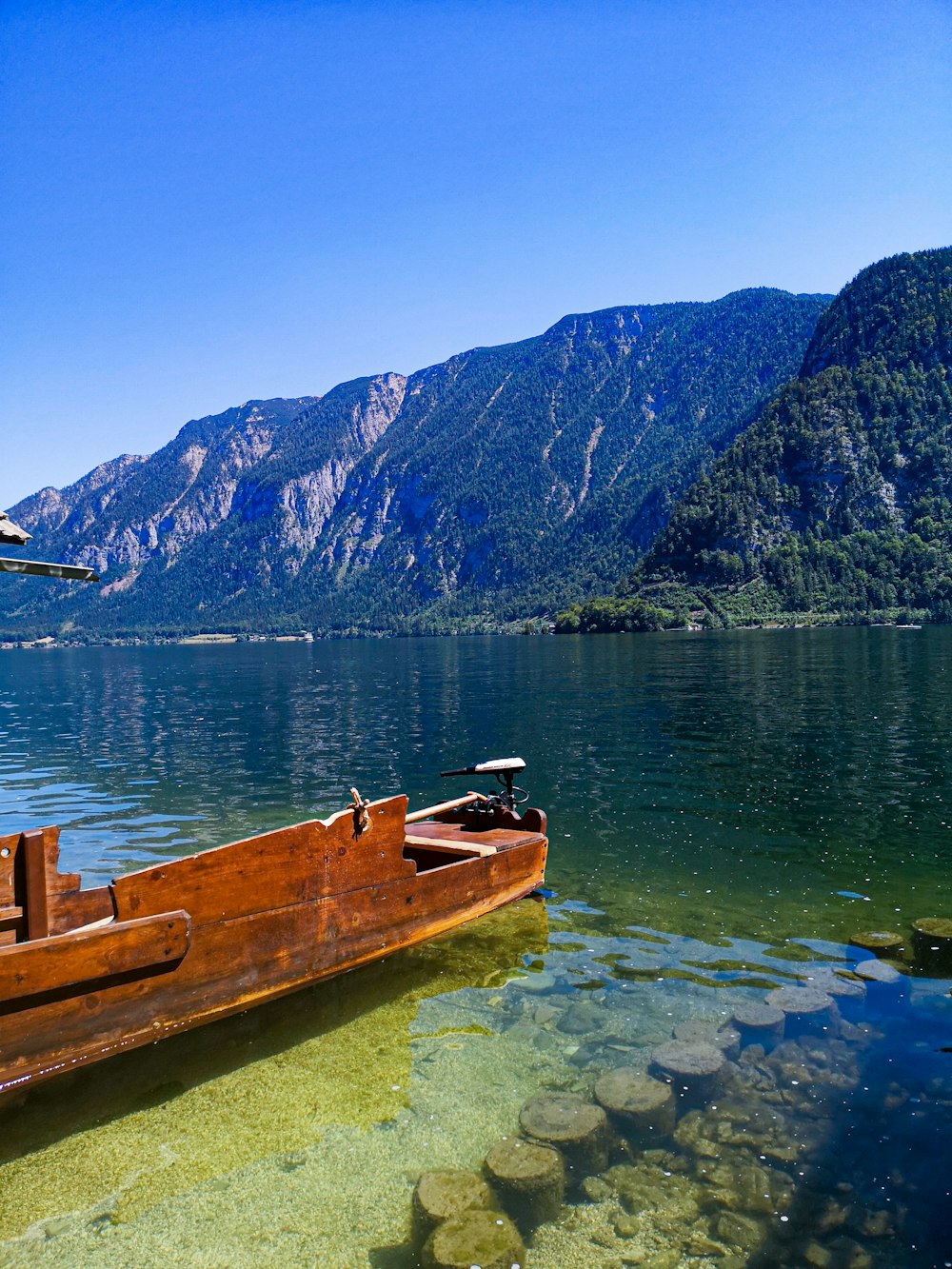 brown wooden boat on water near mountain during daytime