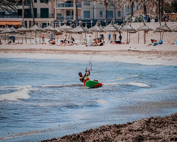 A peaceful moment of a kite surfer resting on the beach, kite laid out on the sand with palm trees swaying.