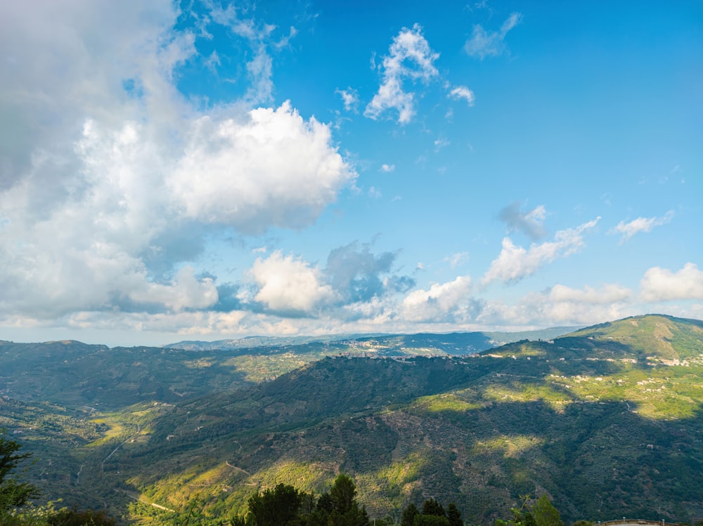 green mountains under blue sky and white clouds during daytime