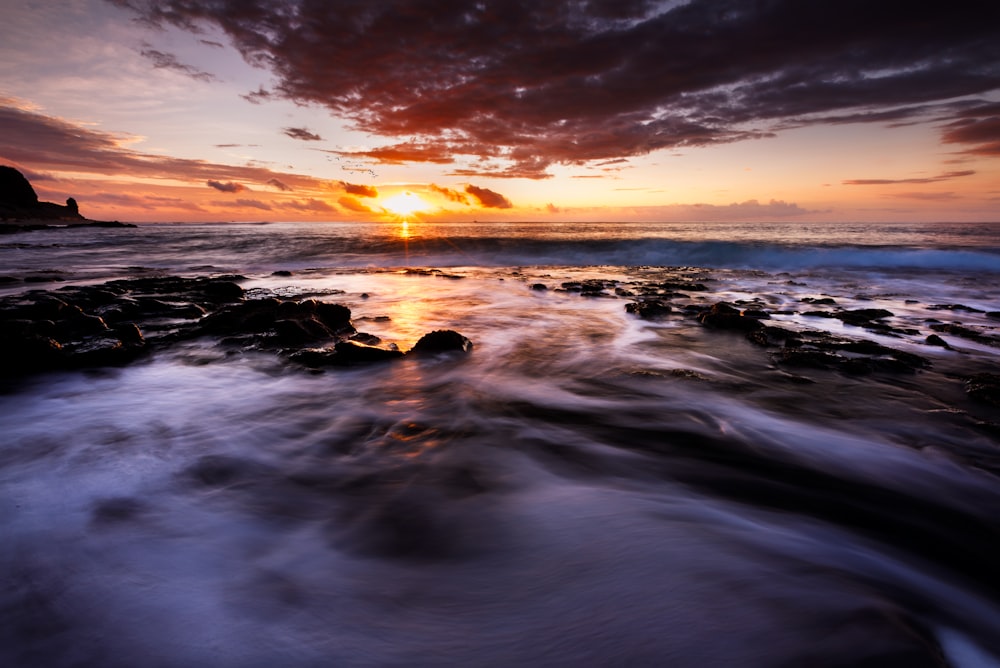 body of water under cloudy sky during sunset