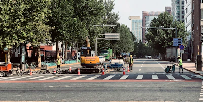 Workers controlling traffic with bright flags at a busy city road construction site.