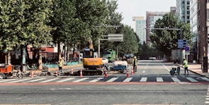 Traffic controllers in safety vests coordinating at a roadside construction area during daylight.