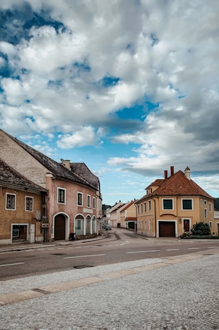 A charming European village street lined with colorful houses and blooming flowers under a bright sky.