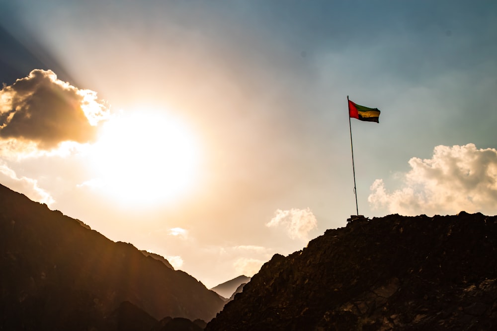 a flag on top of a mountain under a cloudy sky