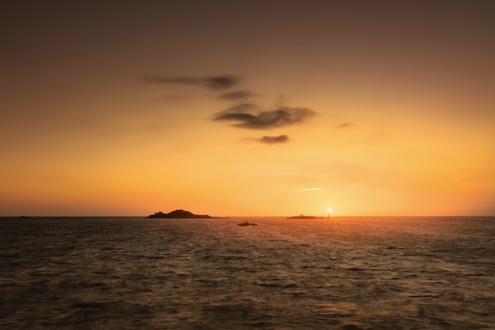 silhouette of mountain beside sea during sunset