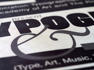 A close-up view of stylized typography featuring bold and decorative lettering with a focus on the word 'TYPOGRAPHY'. The text is set against a textured background with a combination of large, bold letters and elegant curves.