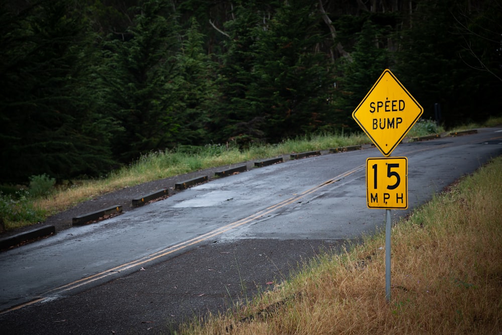 a yellow speed bump sign sitting on the side of a road