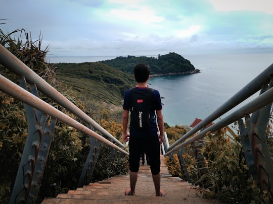 man in red and black jacket standing on brown wooden bridge during daytime in Kincir Angin Pulau Perhentian Malaysia