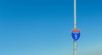 A California Interstate 5 road sign attached to a tall pole with a clear blue sky in the background.