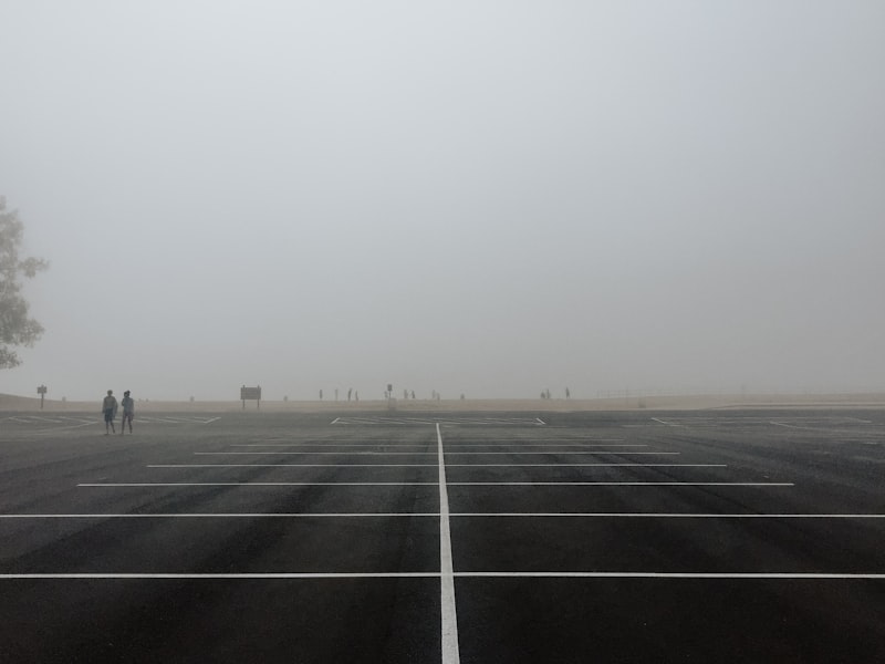 Black asphalt parking lot surface with white line markings