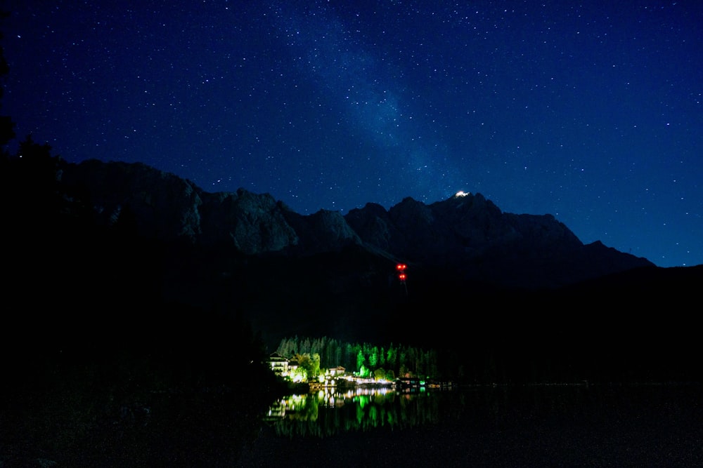 green trees near lake under blue sky during night time