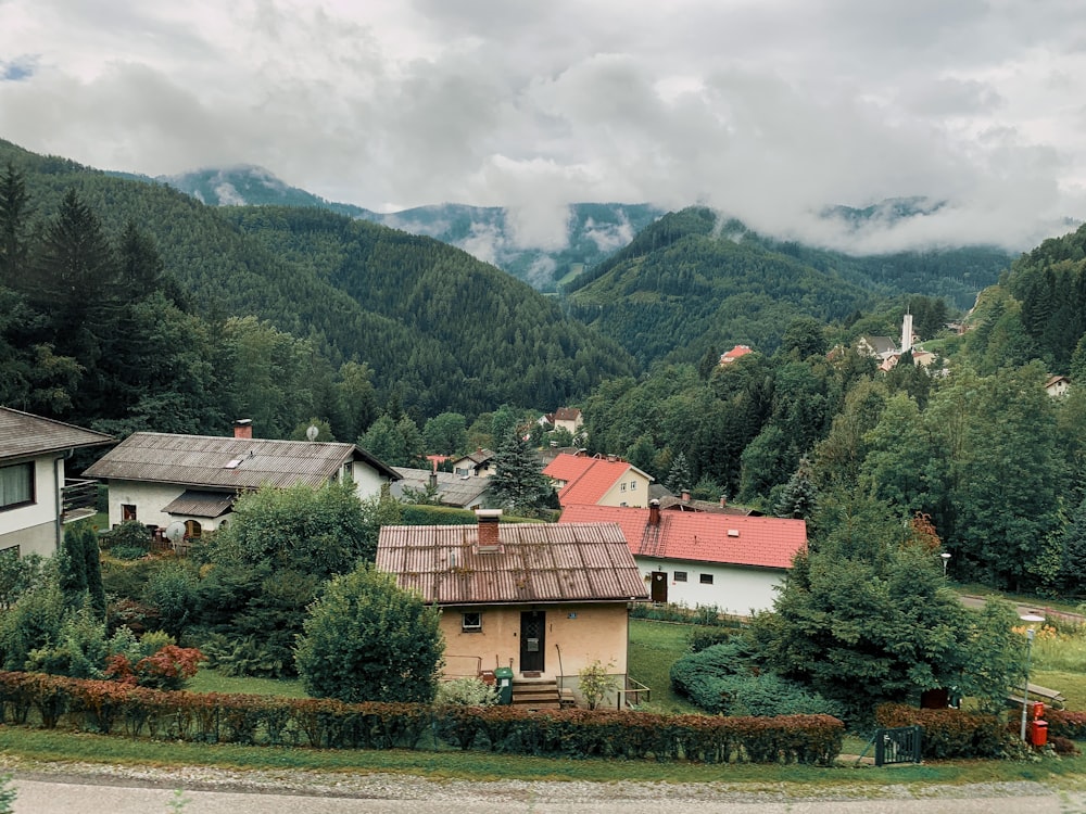 brown and white concrete house near green trees and mountains during daytime