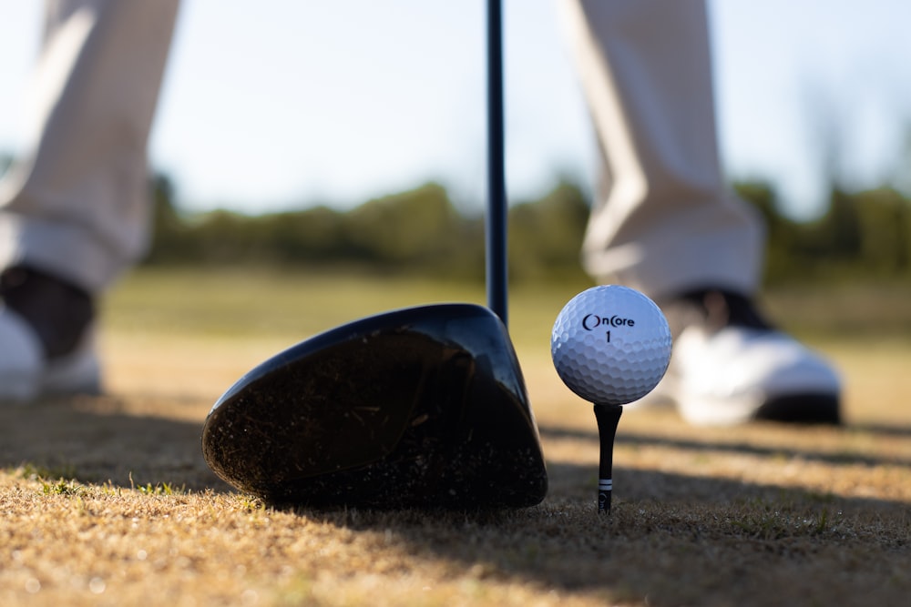 weißer Golfball auf schwarzem Golfschläger
