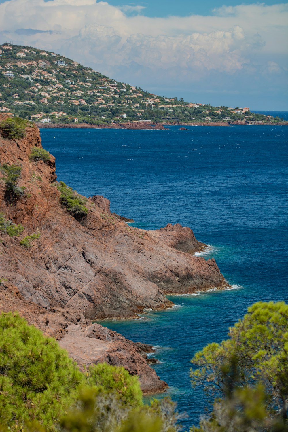 Montaña marrón y verde junto al mar azul durante el día