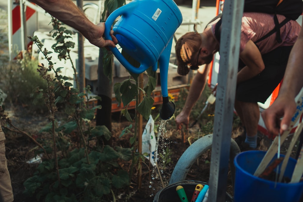 boy in blue tank top holding blue plastic bucket