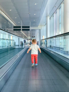 girl in white jacket and blue skirt walking on gray escalator