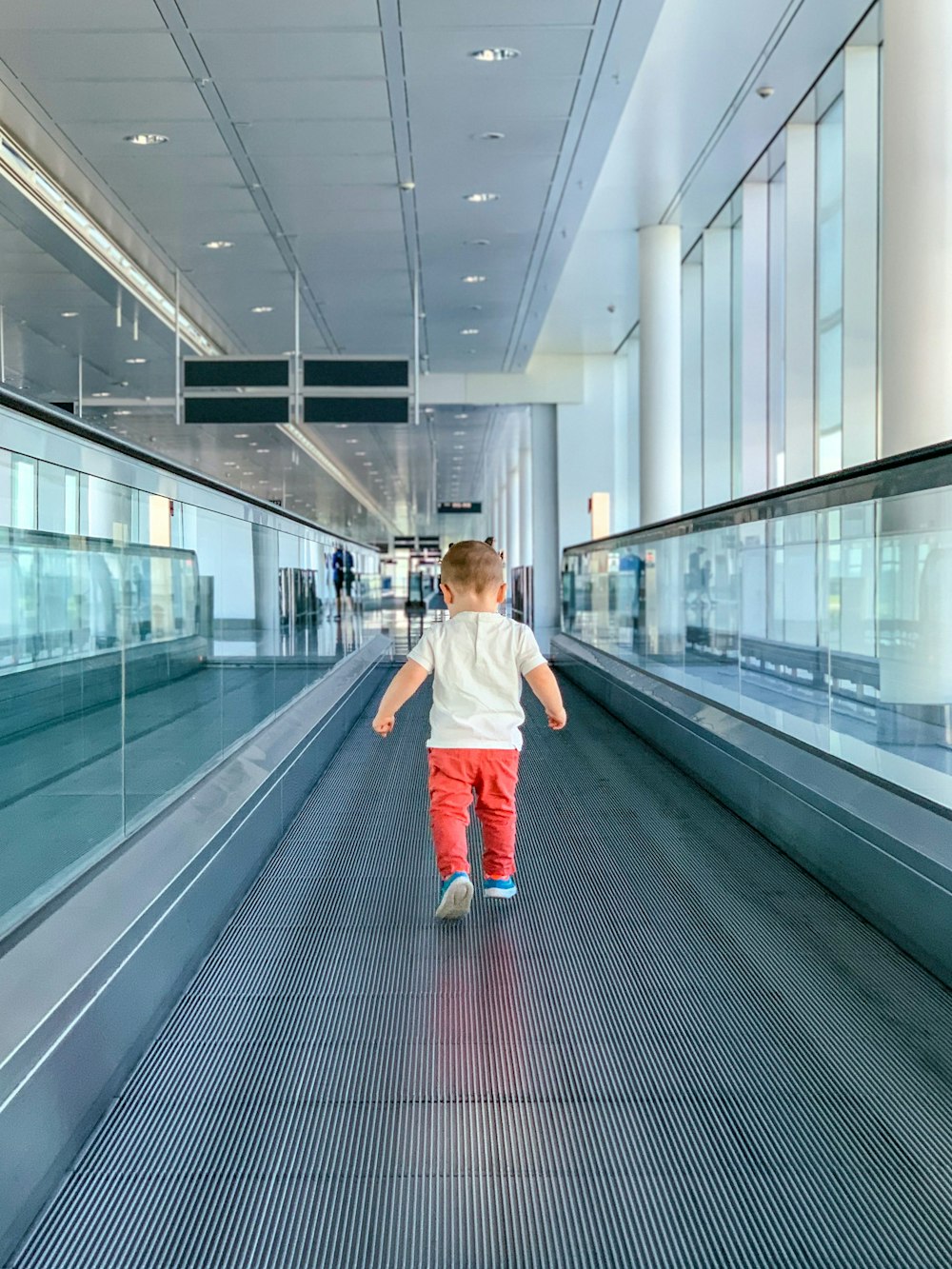 girl in white jacket and blue skirt walking on gray escalator