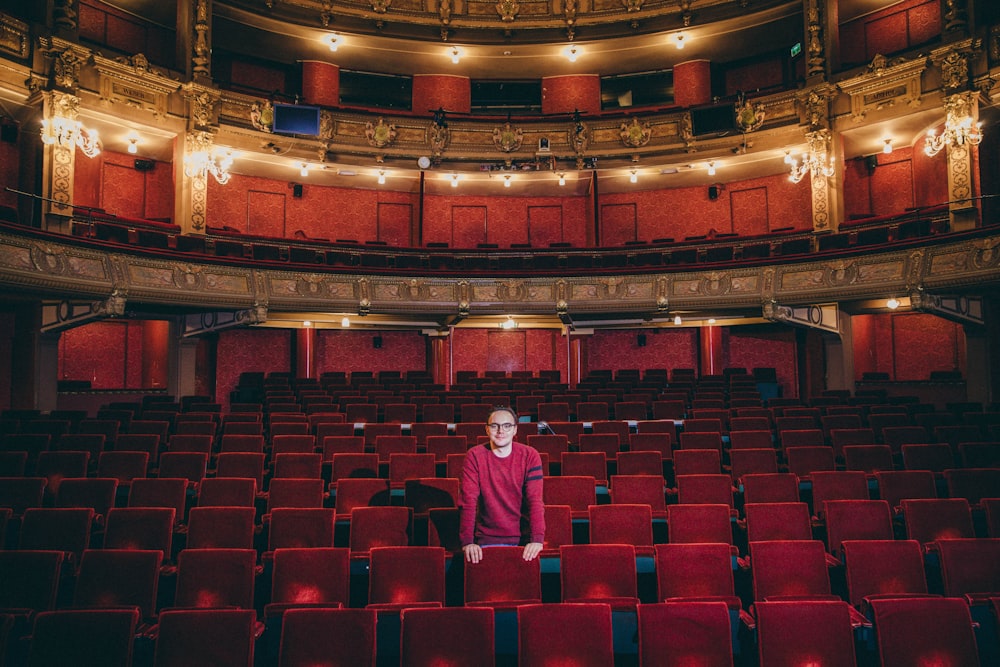 a man in a red shirt sitting in a red auditorium