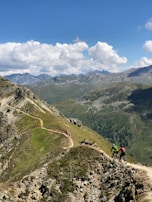Mountain bikers navigating a rugged trail with stunning mountain views in the distance.