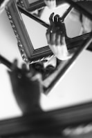 grayscale photo of person holding mirror