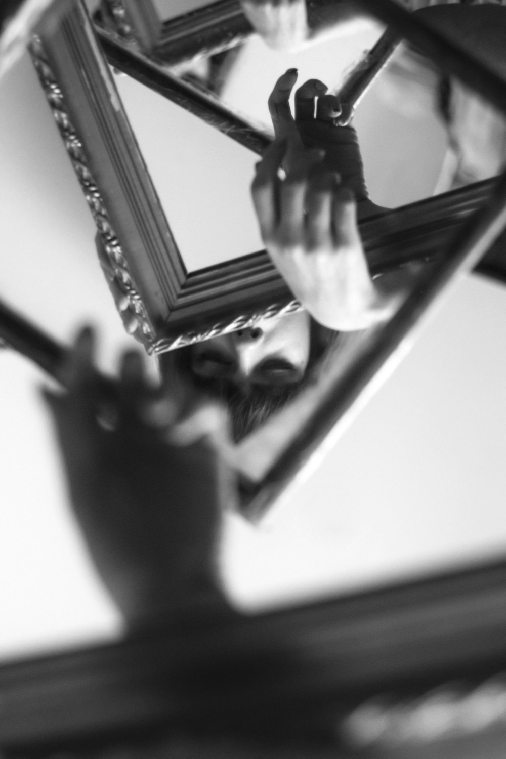 grayscale photo of person holding mirror