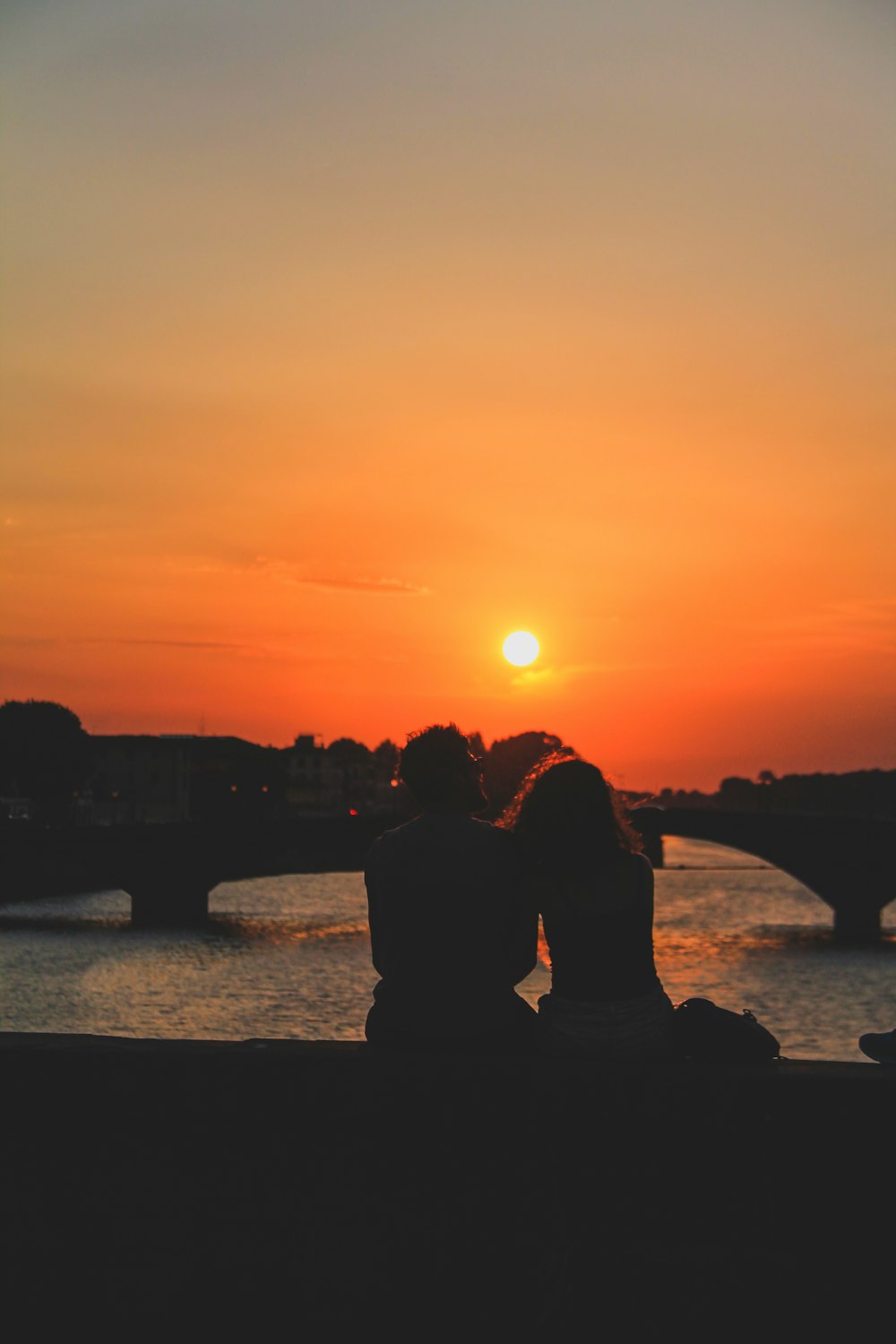 silhouette of people standing near body of water during sunset