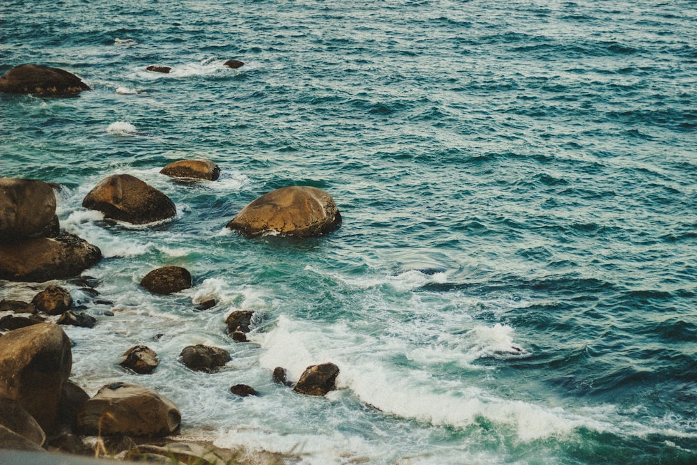 brown rocks on body of water during daytime