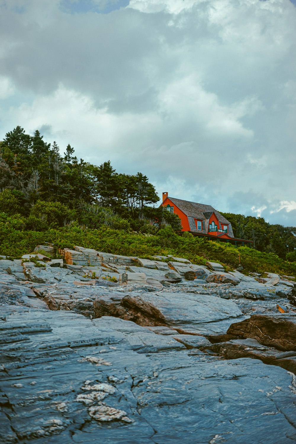 red and black house on rocky shore under cloudy sky during daytime